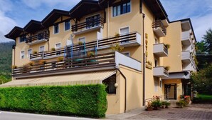 A multi-story hotel with balconies, a covered entrance, and a mountain backdrop. - Hotel Dolomiti Levico (Levico Terme)