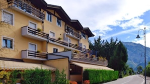A multi-story hotel with balconies, a covered entrance, and a view of mountains. - Hotel Dolomiti Levico (Levico Terme)