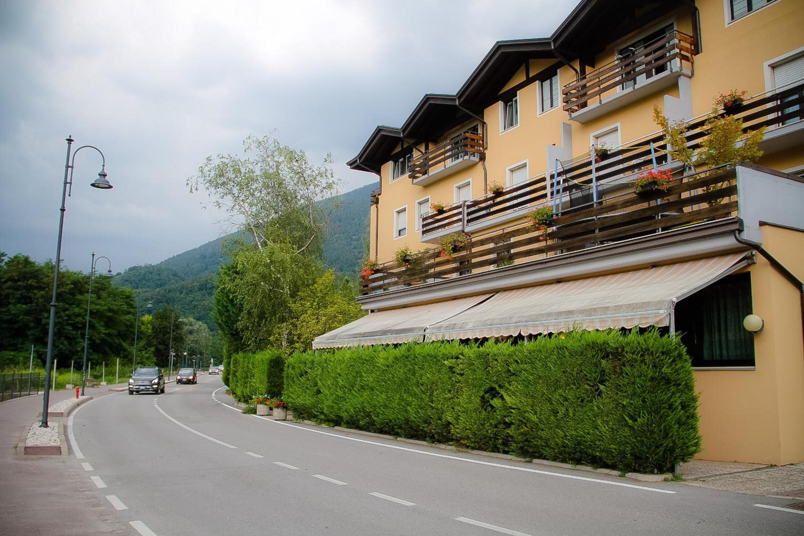 Un edificio a più piani con balconi, un tendone e una strada con auto.