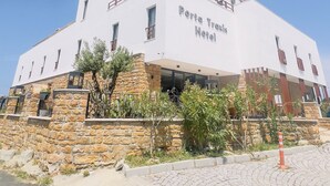Un edificio blanco con base de piedra y un cartel que dice "Porta Traris Hotel".