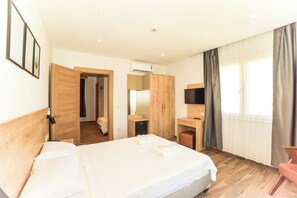 A hotel room with a bed, a desk, a TV, and a wardrobe. - Porta Trakis Hotel (Gökçeada)