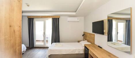A hotel room with a bed, a wooden bench, a TV, and a large mirror.