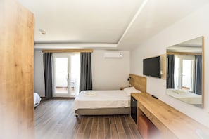 A hotel room with a bed, a wooden bench, a TV, and a large mirror. - Porta Trakis Hotel (Gökçeada)