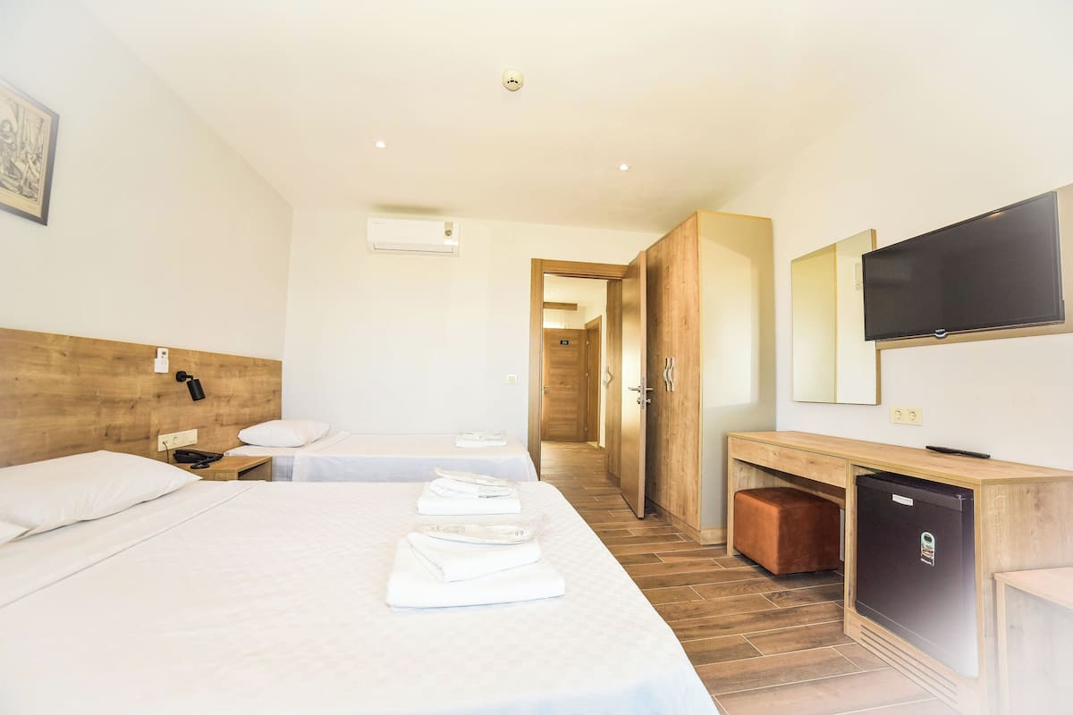 A hotel room with two beds, a desk, a television, and a refrigerator.