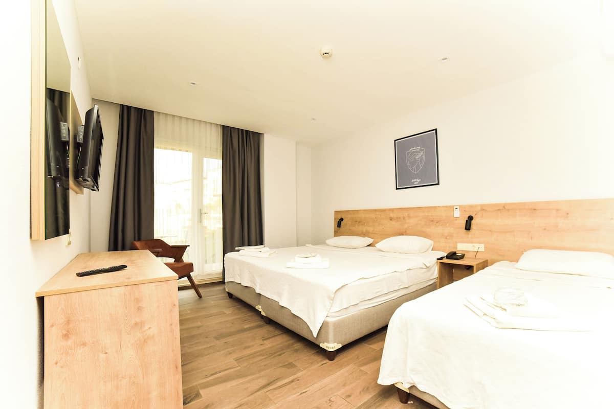 A hotel room with two beds, a desk, a chair, and a large window with curtains.