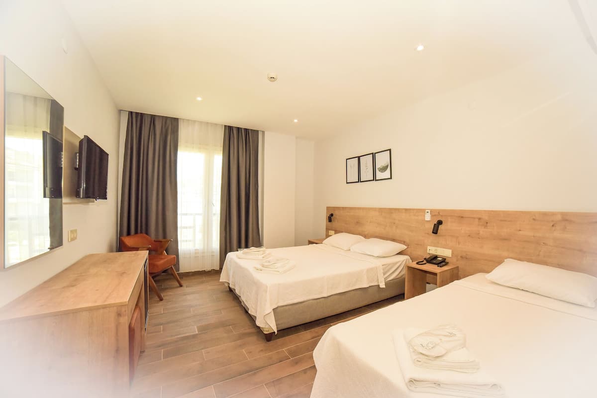 A hotel room with two beds, a desk, a chair, a TV, and a window with curtains.