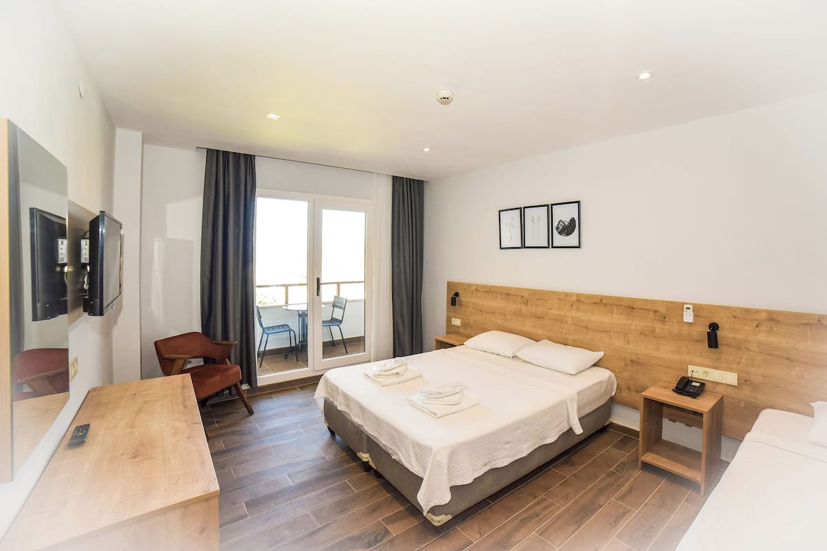 A modern hotel room with a large bed, a wooden headboard, a desk, and a chair.
