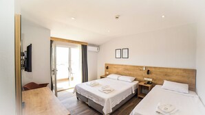 Habitación de hotel con dos camas, cabecero de madera, televisor de pantalla plana, escritorio y puerta corredera de cristal que da a un balcón.
