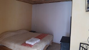 A room with a bed, a wooden ceiling, a white wall, and a small black cabinet. - Cabaña Miroji (Zacatlán)