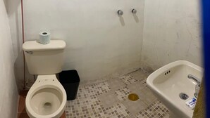 A small bathroom with a toilet, a black trash bin, a sink, and a tiled floor. - Cabaña Miroji (Zacatlán)
