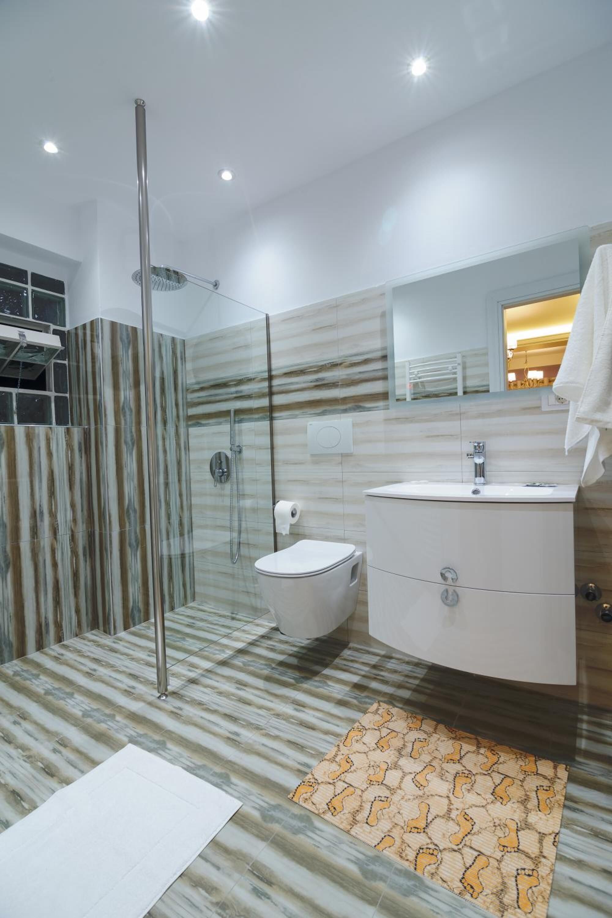 A modern bathroom with a glass-enclosed shower, a white toilet, and a vanity with a mirror.