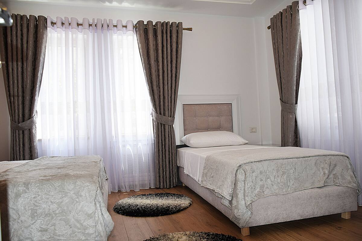 Une chambre à coucher avec un lit, deux tables de chevet et une fenêtre avec des rideaux.