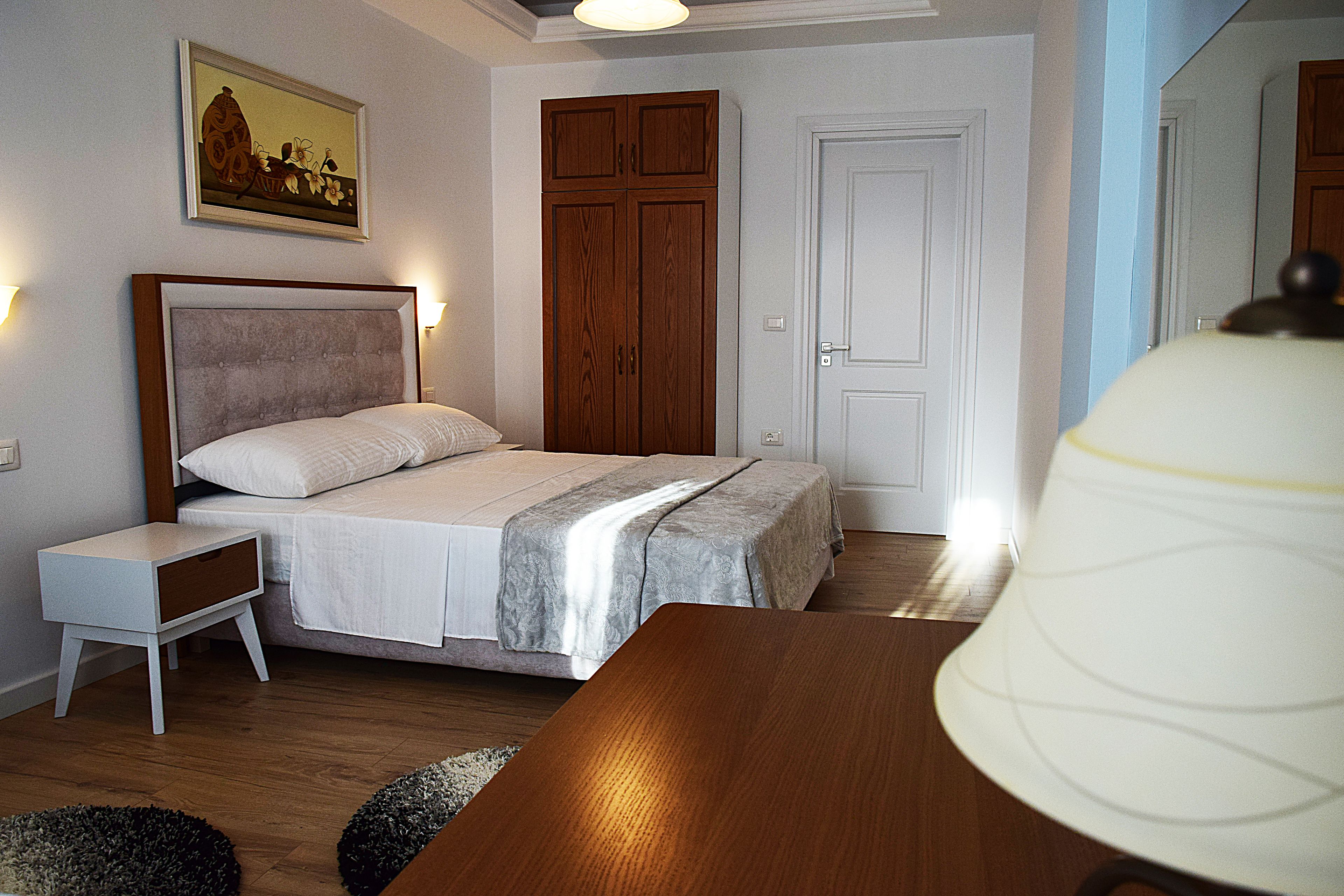 Un dormitorio con una cama, mesita de noche, armario de madera y una lámpara.