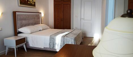 Un dormitorio con una cama, mesita de noche, armario de madera y una lámpara.