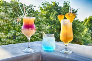 Three cocktails on a table with a green leafy background. - Eagles Philadelphia Hotel (Korçë)