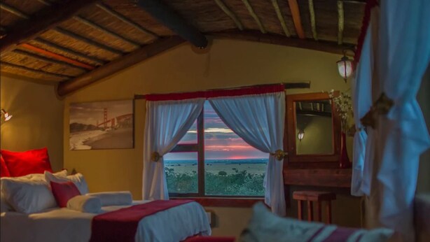 A room with a bed, a small table, and a window with curtains.