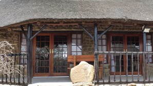 A rustic stone building with a thatched roof, wooden doors, and a stone bench outside.