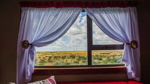 A room with a window overlooking a savannah landscape.