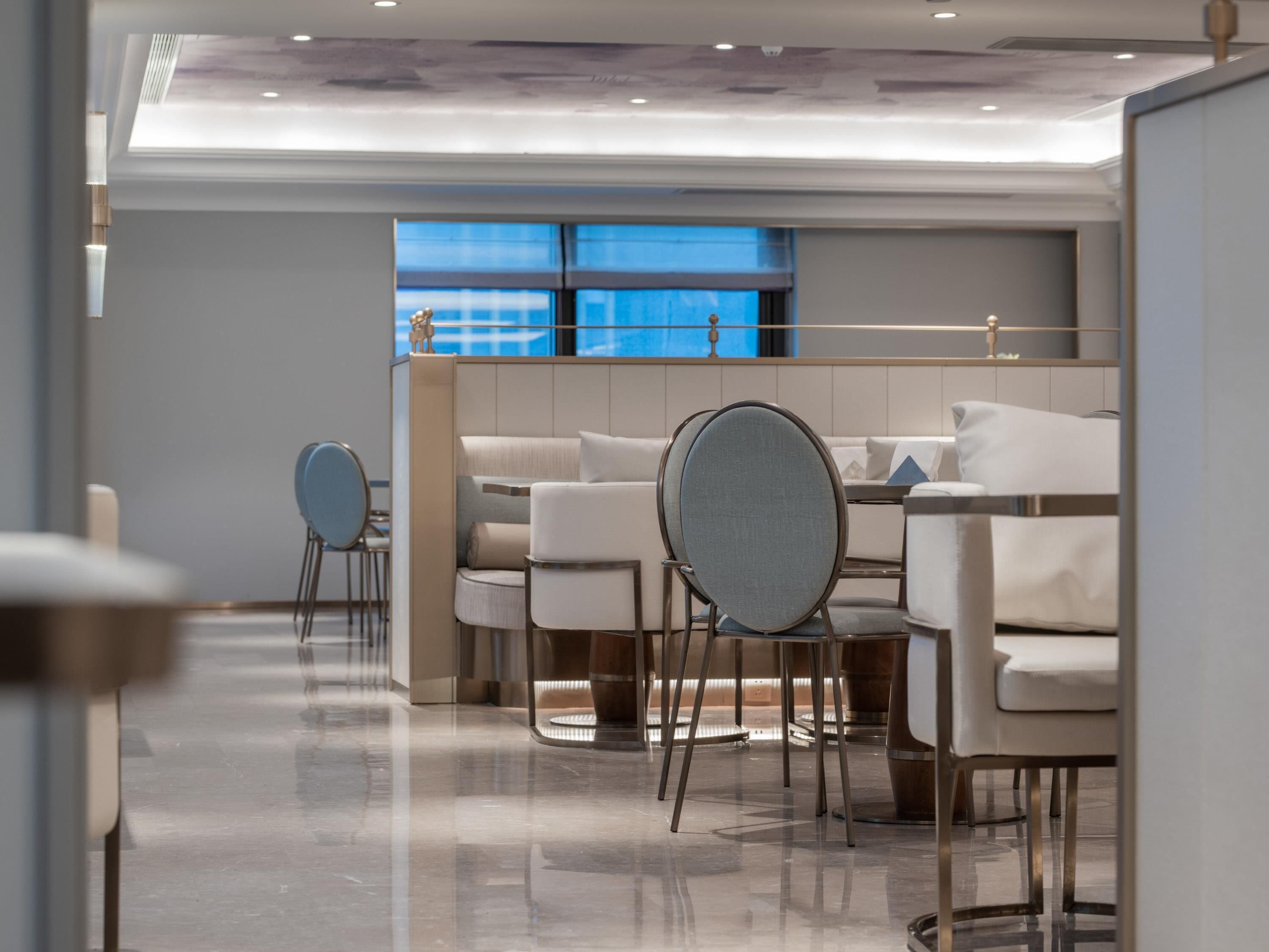 Eine moderne Hotellobby mit einer Sitzecke, einem Empfangsbereich und Blick auf die Stadt durch große Fenster.