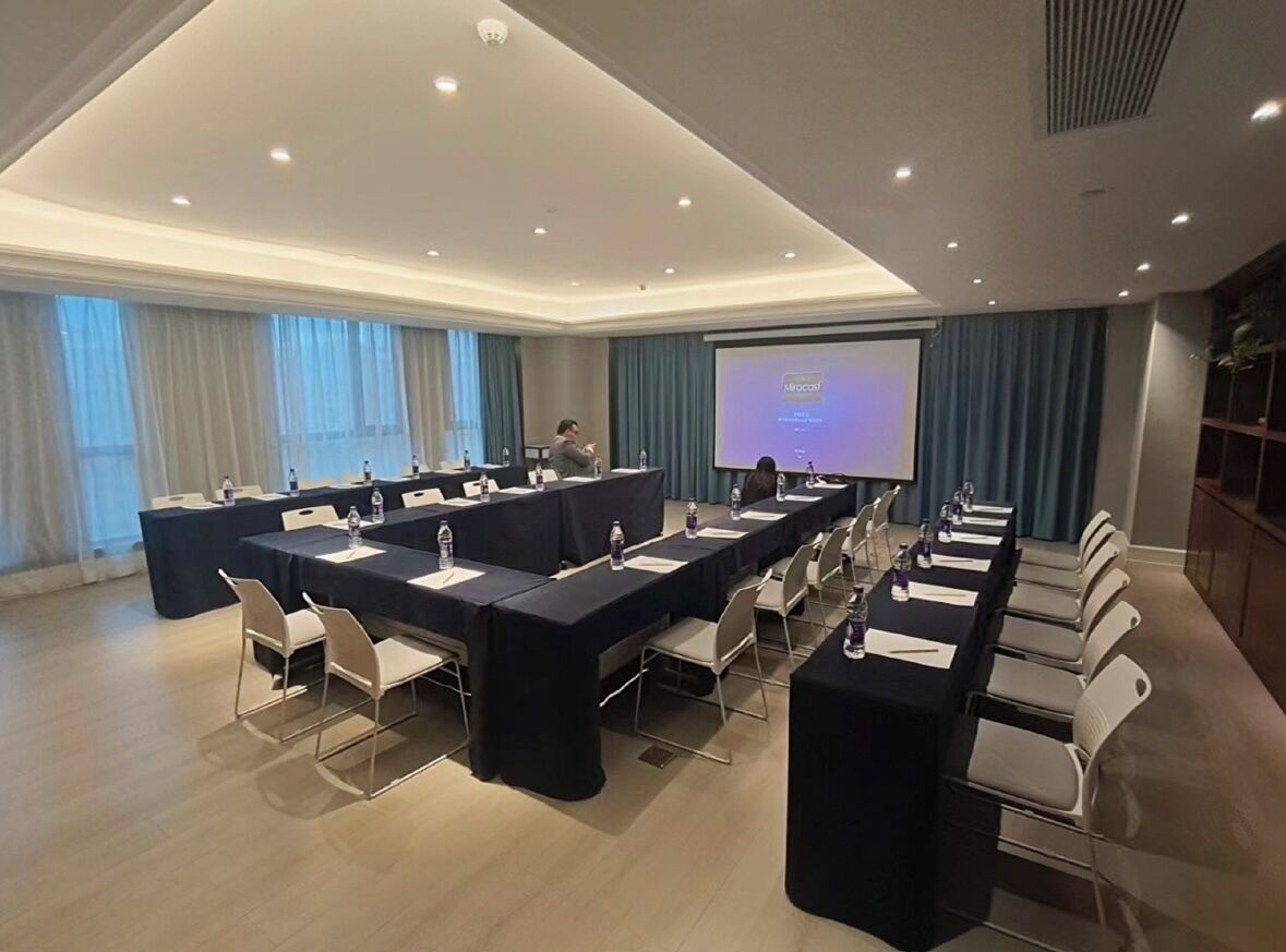 Un salón de conferencias con una larga mesa, sillas, una pantalla y un atril.