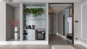 A modern hotel room with a walk-in closet, a small seating area, and a bathroom with a robe hanging. - Mercure Xian North (Xi'an)