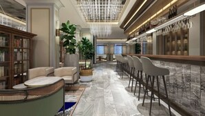 A modern hotel lobby with a marble floor, a bar area with stools, a seating area with sofas and a coffee table, and a large potted plant. - Mercure Xian North (Xi'an)