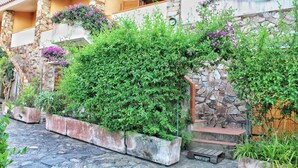 A courtyard with stone walls, potted plants, and a stone staircase. - Porto Rotondo Garden Flats (Olbia)
