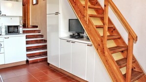 A kitchen with white cabinets, a microwave, and a wooden staircase. - Porto Rotondo Garden Flats (Olbia)