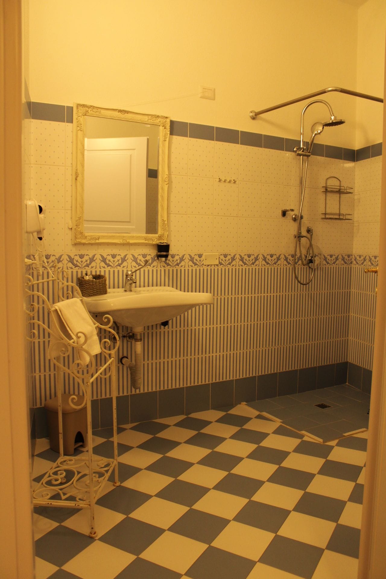 Un baño con piso a cuadros, un lavamanos, un espejo y una ducha.