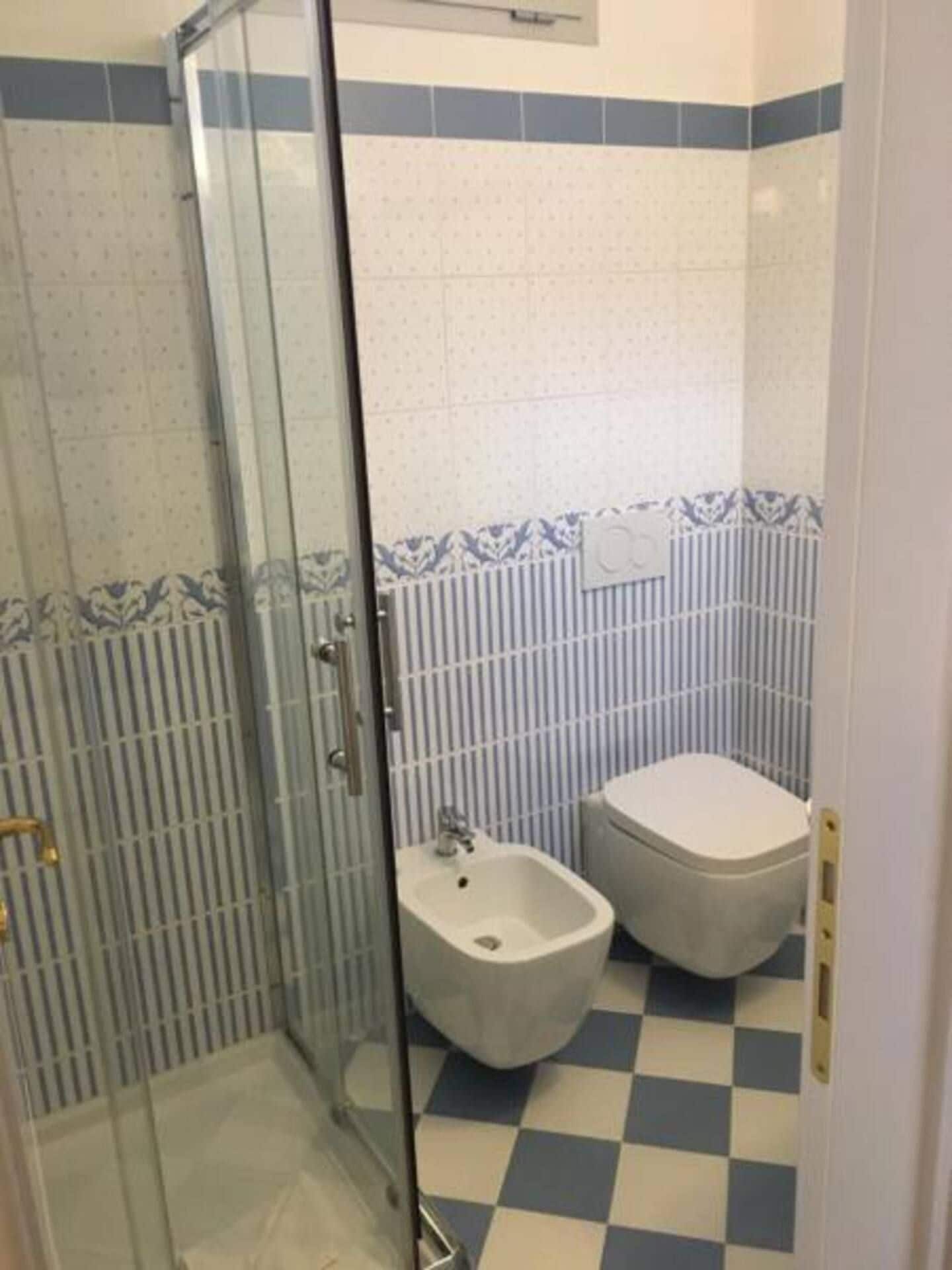 A bathroom with a glass shower enclosure, a bidet, and a toilet.