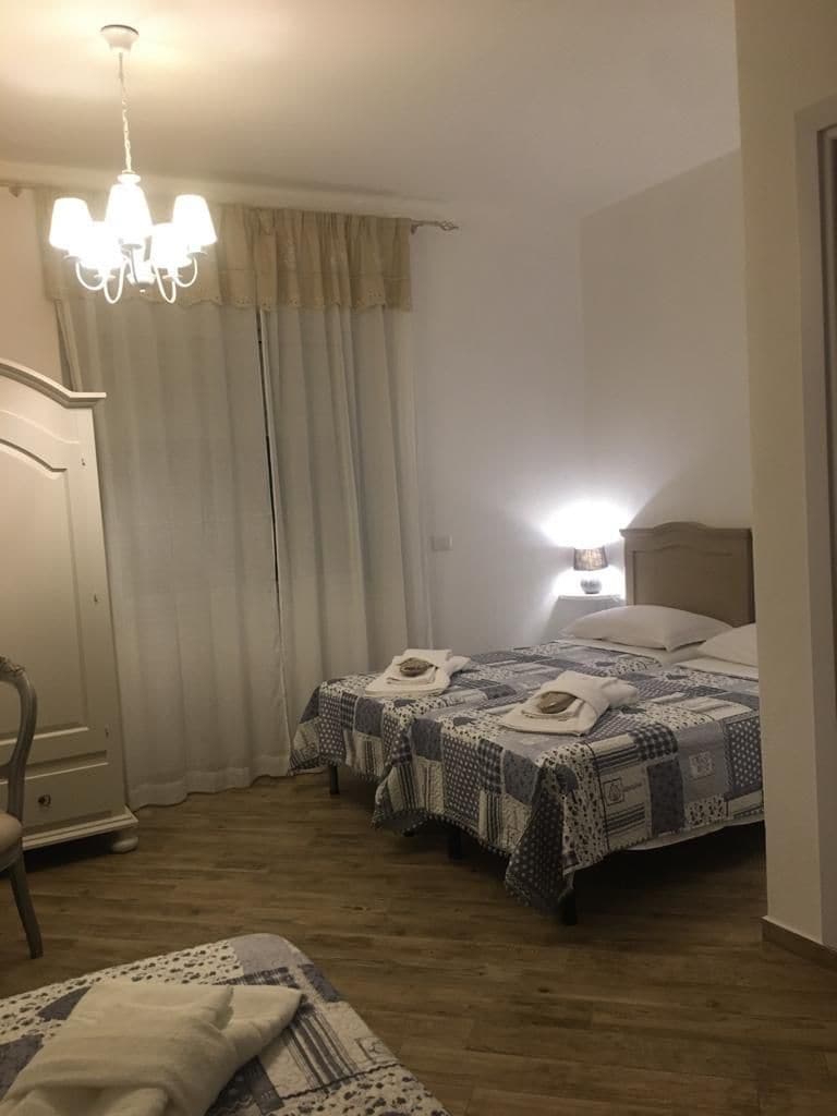 A hotel room with a bed, a nightstand, a chair, and a chandelier.