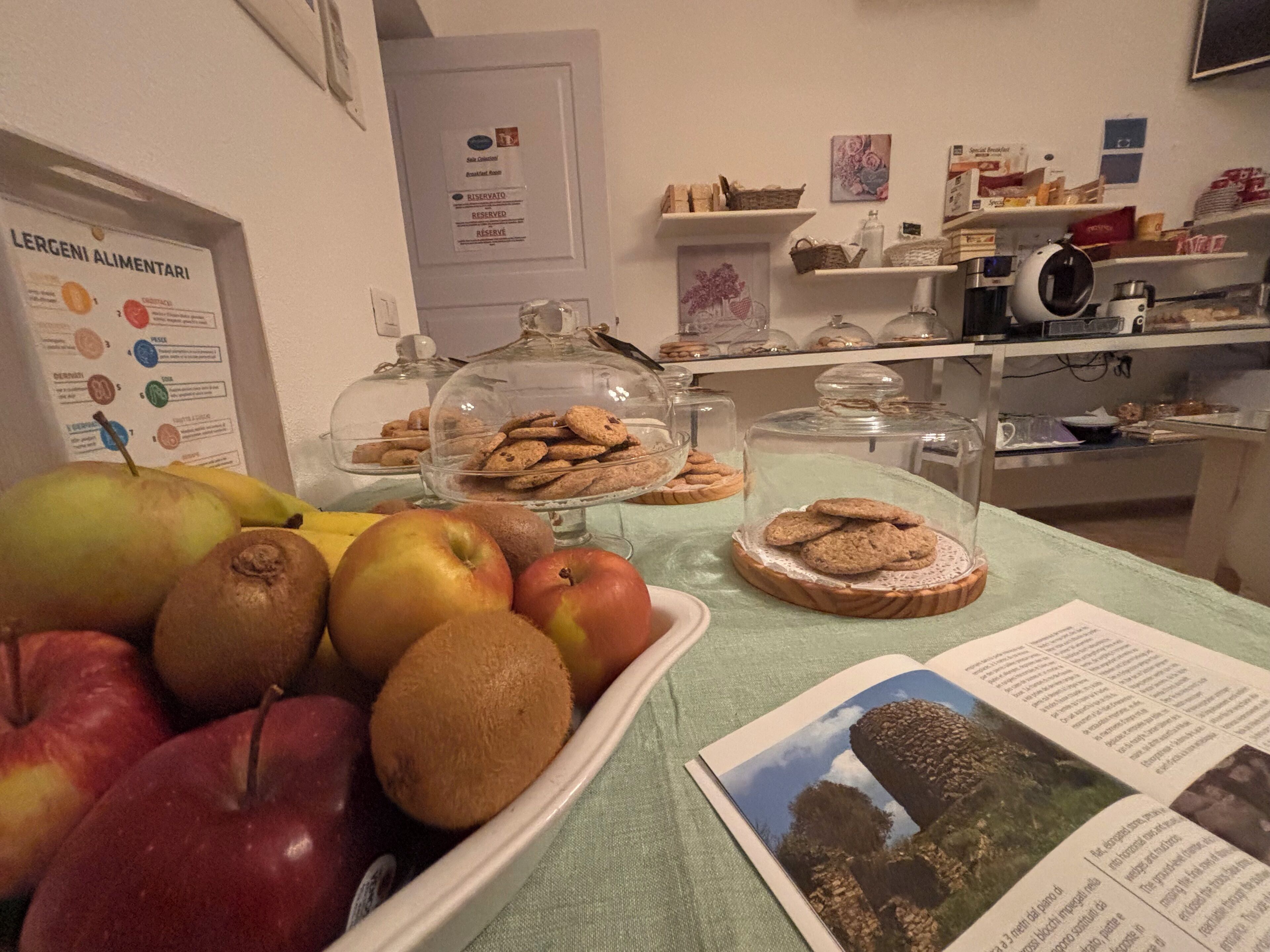 A buffet table with a variety of fruits and cookies, a menu board, and a coffee machine.