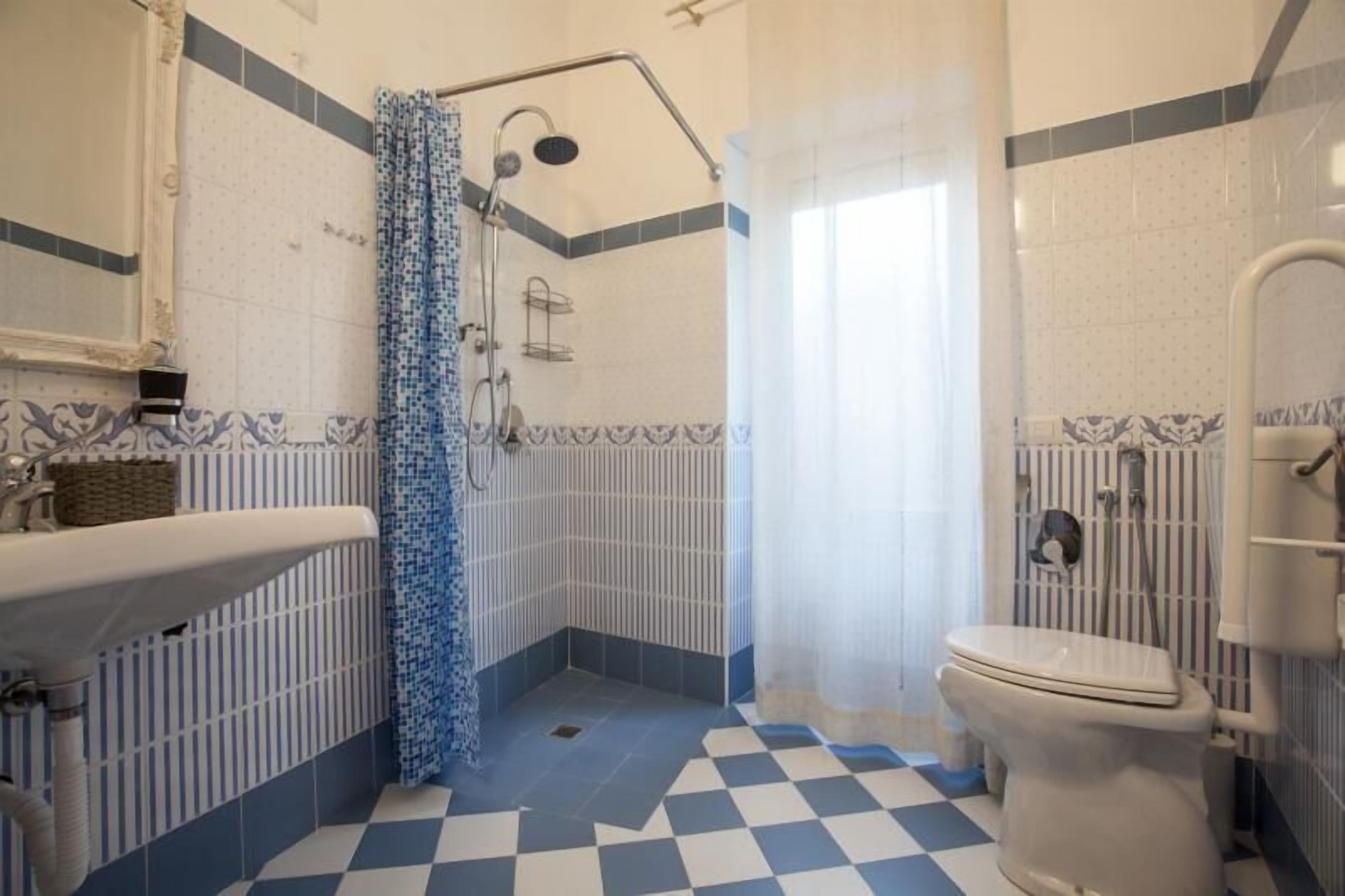 A bathroom with a checkered floor, a bathtub, a toilet, and a sink.