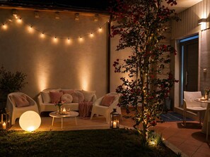 Un espacio al aire libre con sillones, sillas, una mesa redonda y una planta en maceta.