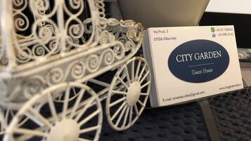 A white metal carriage with intricate designs, a business card for City Garden Guest House, and a website URL.