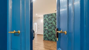 Ein Flur mit blauen Türen, Holzboden und einer Wand mit einem grünen Blattmuster.