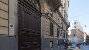 Eine Straße mit einer großen, braunen Tür, einem parkenden Auto und einem Gebäude im klassischen Stil.