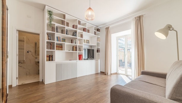 Ein modernes Wohnzimmer mit Bücherregal, einer Couch und einem Fernseher.