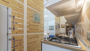 A kitchen with wooden panel walls, a gas stove, and a coffee maker. - Vittorio Emmanuele & Colosseo Studio (Rome)