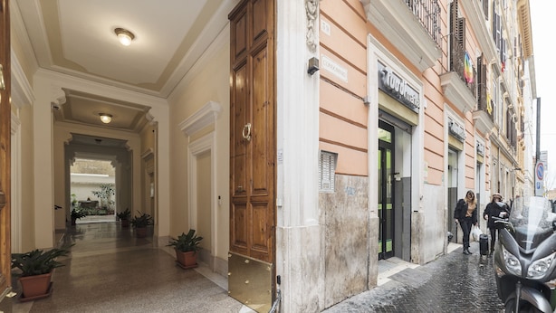 A hotel entrance with a wooden door, potted plants, and a cobblestone street. - Vittorio Emmanuele & Colosseo Studio (Rome)