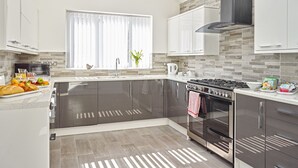 A modern kitchen with a central island, stainless steel appliances, and a large window with curtains. - 88 Anfield (Liverpool)