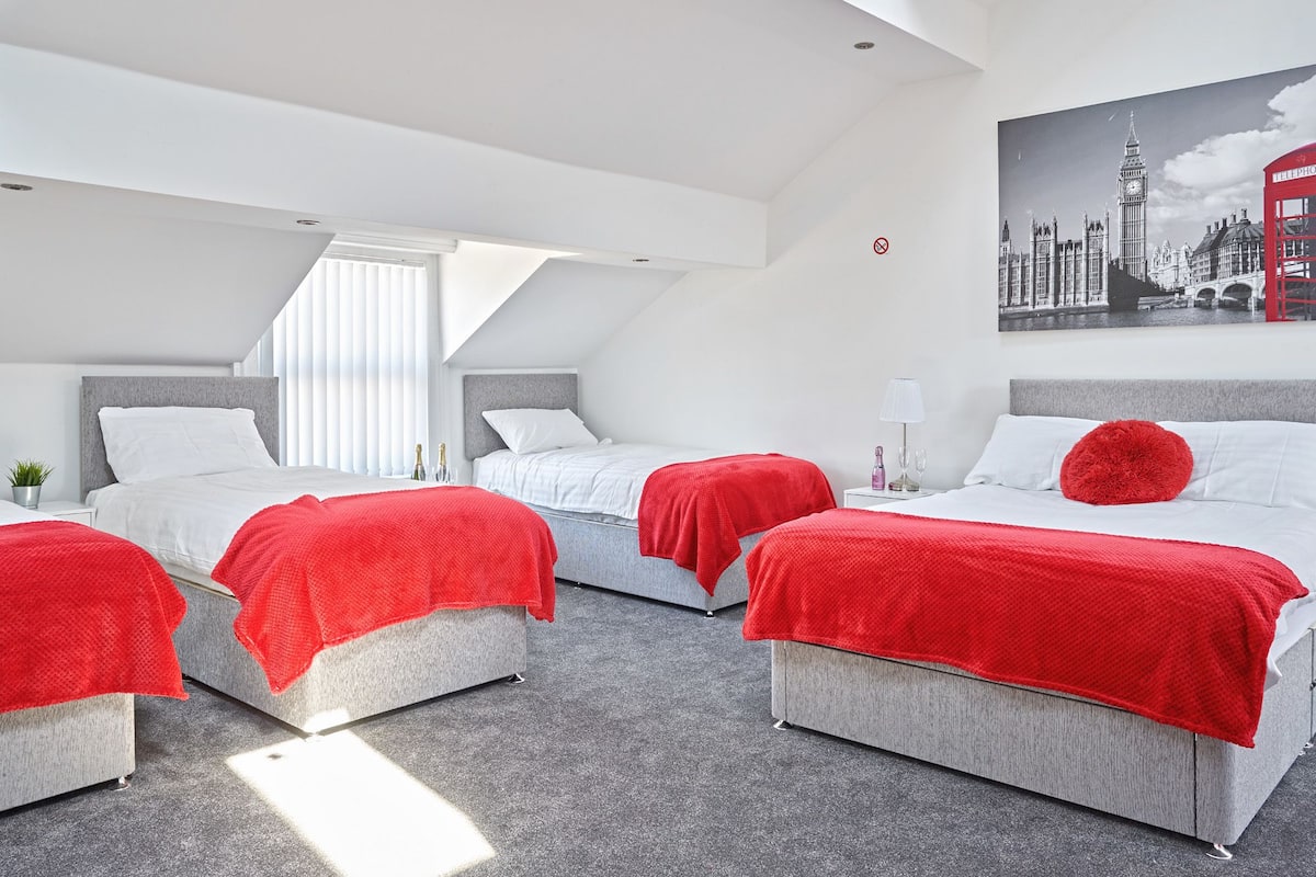 A modern hotel room with two beds, a skylight, and a cityscape painting.