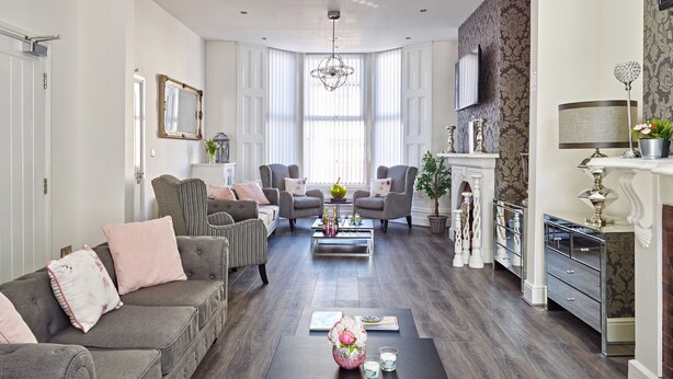 A spacious living room with a fireplace, a chandelier, and a television mounted on the wall. - 88 Anfield (Liverpool)