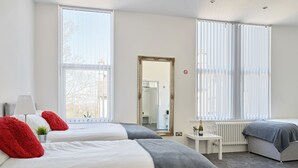 A hotel room with two beds, a small table, a mirror, and large windows with blinds. - 88 Anfield (Liverpool)