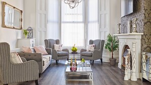 A living room with a fireplace, two armchairs, a sofa, and a coffee table with drinks. - 88 Anfield (Liverpool)