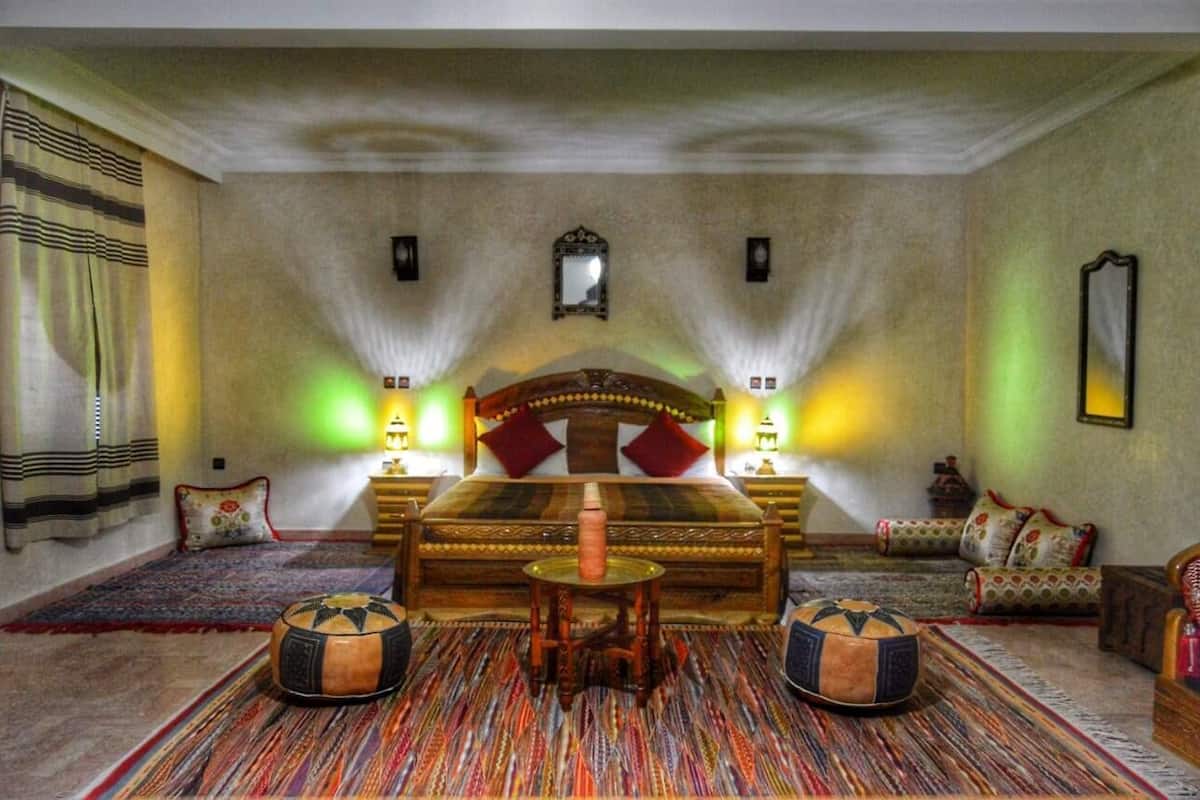 Ein geräumiges Schlafzimmer mit einem großen Bett, zwei Nachttischen, einem kleinen Tisch und einem Schlafsofa.
