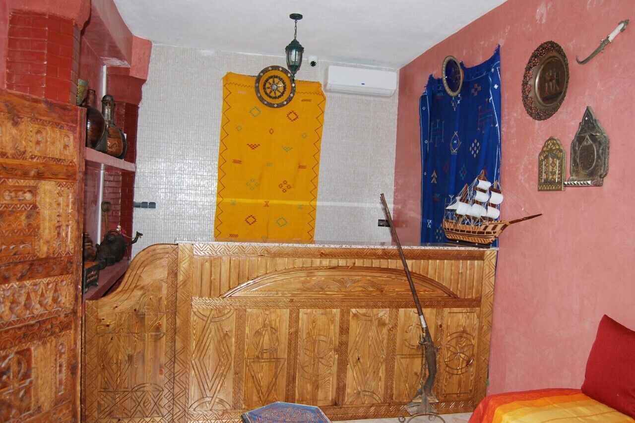 Una habitación con una cama de madera, un modelo de barco en la pared y una cortina estampada.