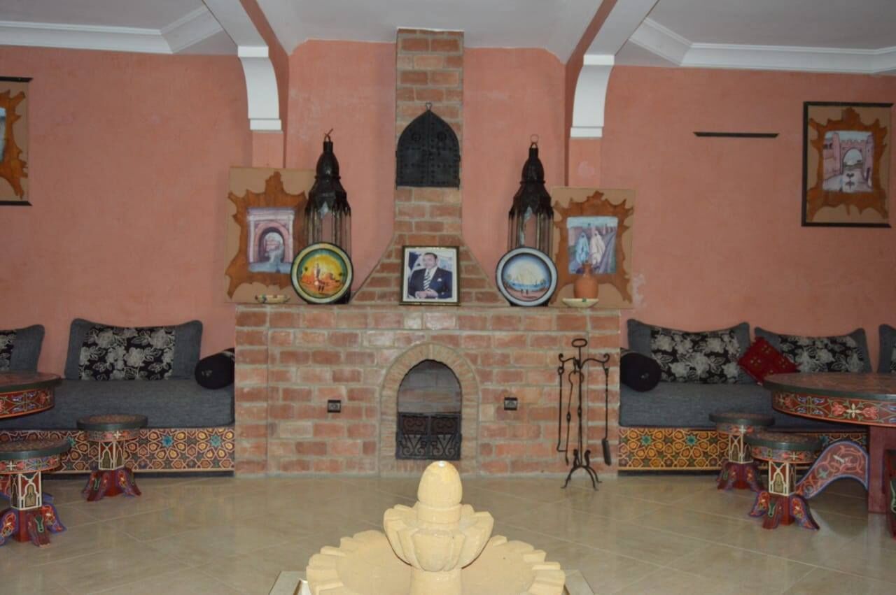 Un accogliente soggiorno con camino in mattoni, divani decorati con motivi e lanterne ornamentali.