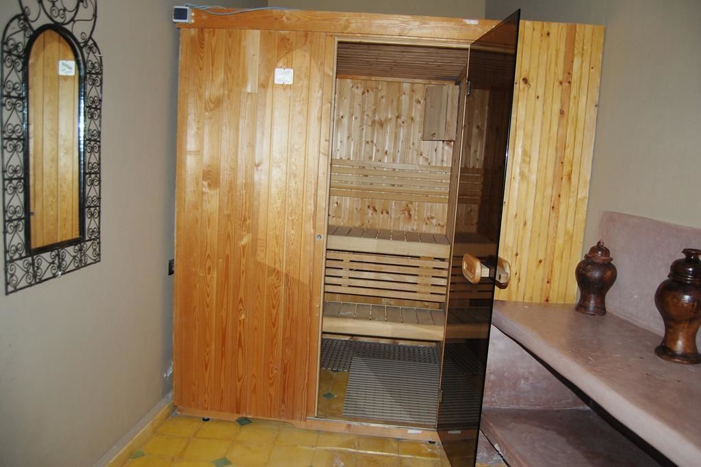 A wooden sauna with a sliding door, a mirror, and a shelf with decorative items.