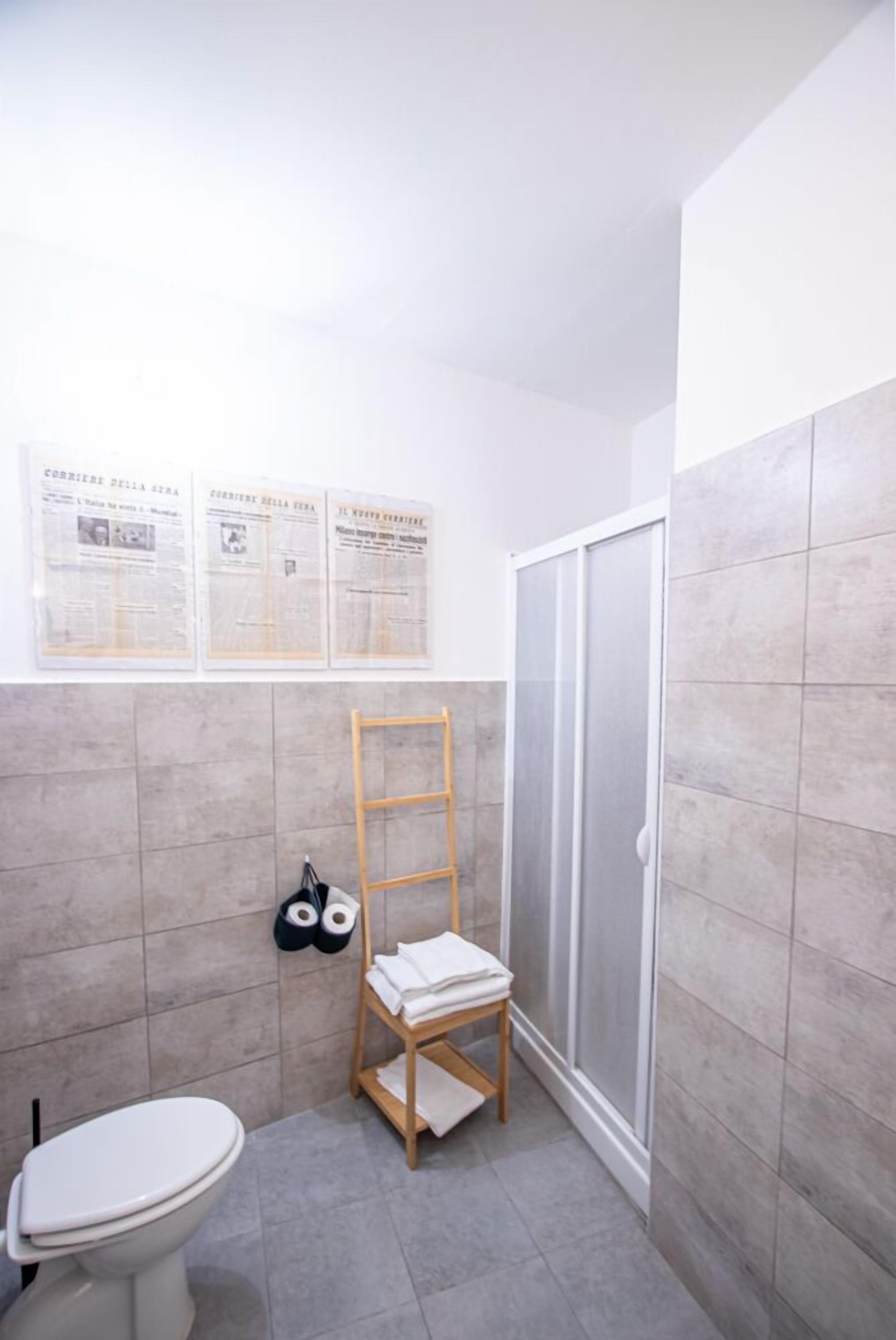 Un baño con inodoro, una escalera de madera, un perchero para toallas y zona de ducha.